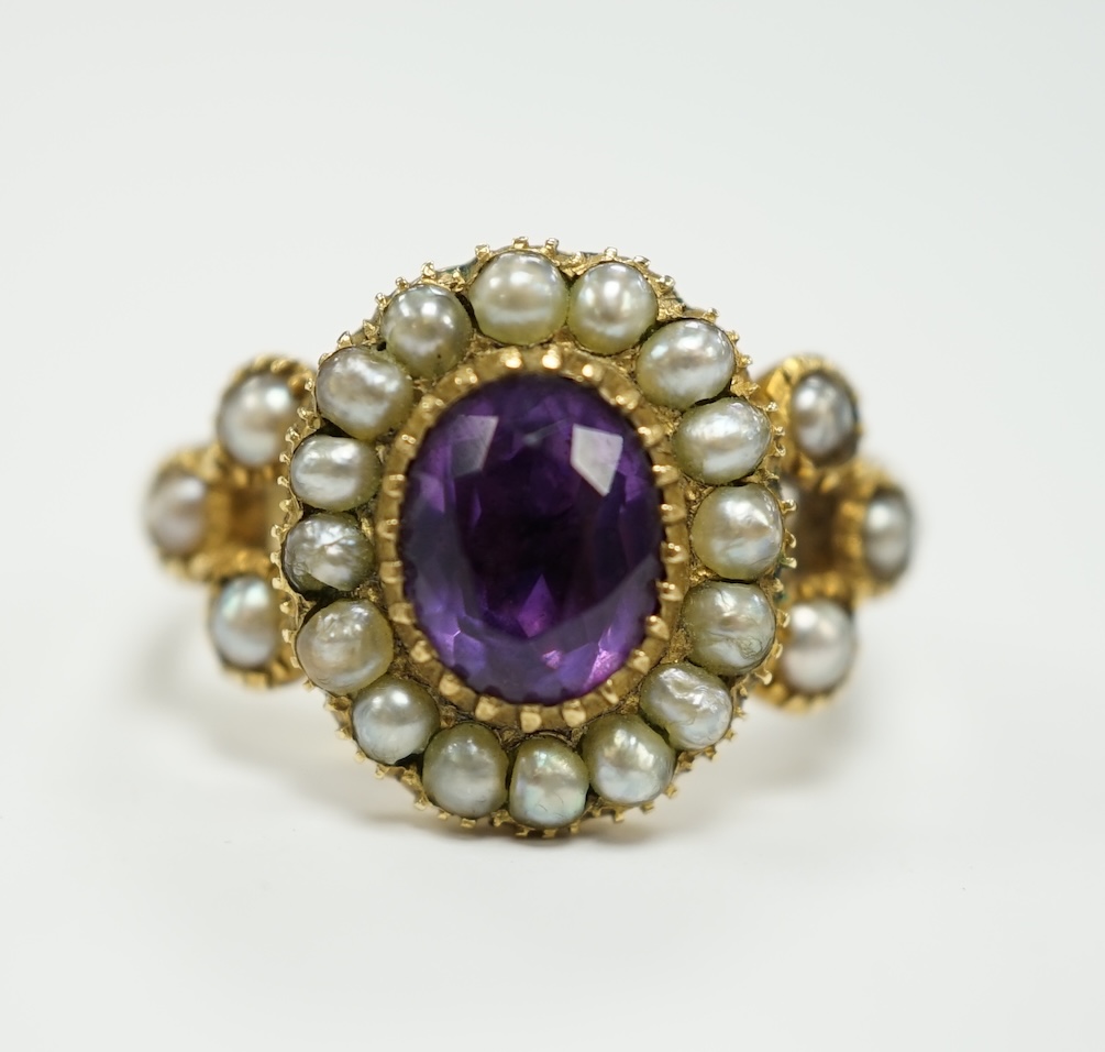 A Victorian yellow metal seed pearl and amethyst set oval cluster ring, size L, gross weight 3.7 grams.